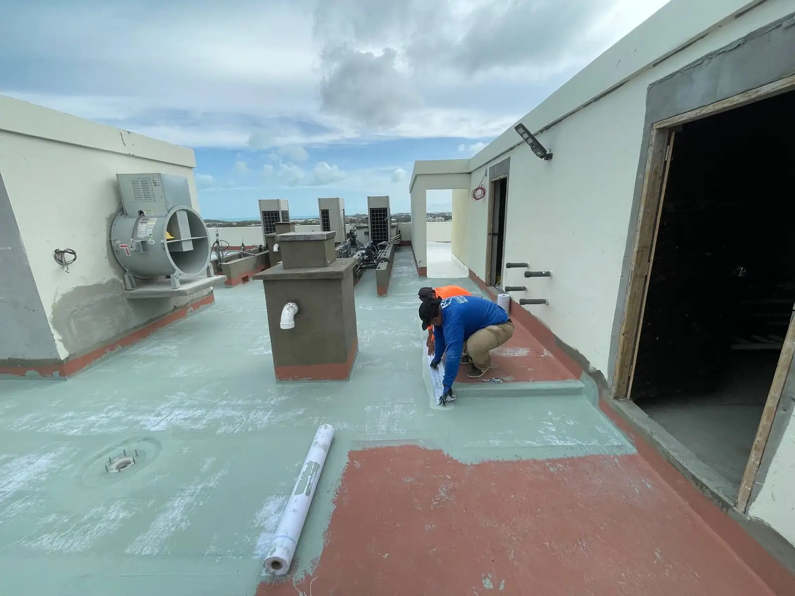 Installer working at a rooftop wall and doorway, St. Regis, Turks and Caicos